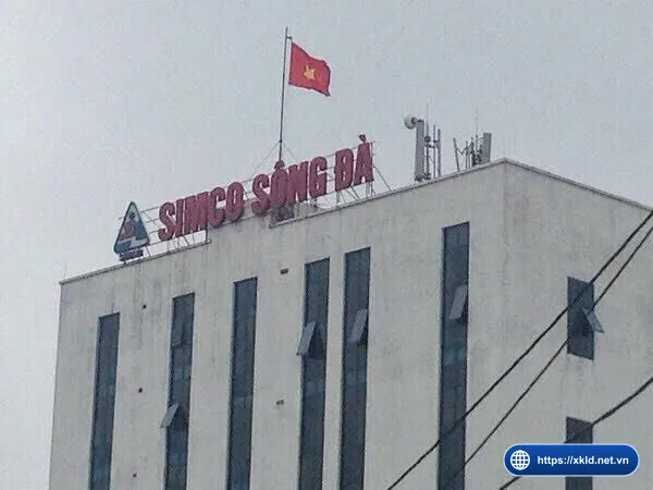 Tòa nhà SIMCO Sông Đà ở Hà Đông, phần trên cùng có biển chữ đỏ SIMCO SÔNG ĐÀ, logo công ty và lá cờ đỏ sao vàng trên nóc nhà