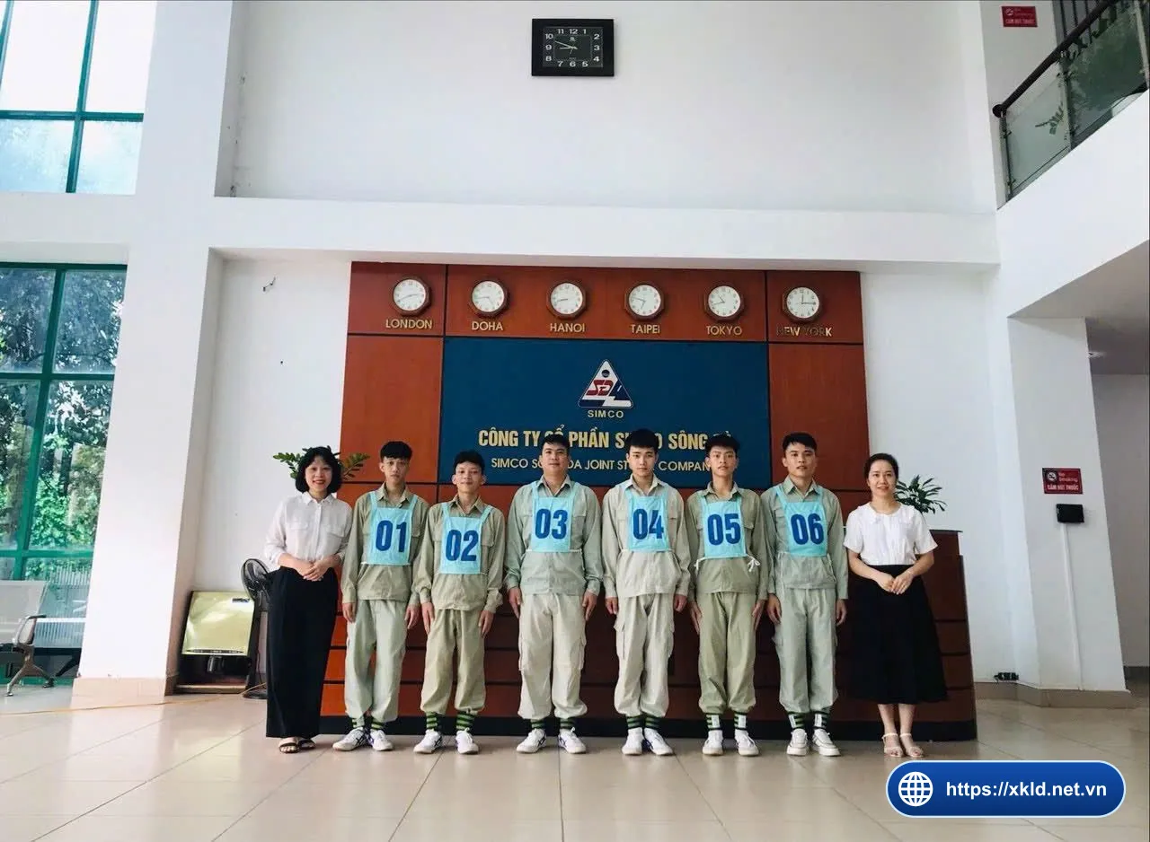 Sáu lao động nam đeo số 01 đến 06 cùng hai nhân viên nữ trước biển SIMCO Sông Đà, chụp lúc phỏng vấn đơn hàng